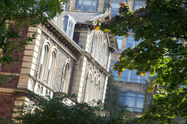 Old and new university buildings among the trees on Woodland Road. 